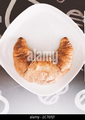 Vertikale Nahaufnahme eines leckeren Croissants in einem weißen Platte Stockfoto