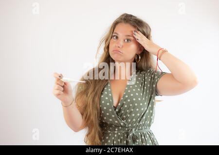 Ziemlich blonde Mädchen in einem grünen Kleid suchen den Test mit der Geste der Sorge Stockfoto