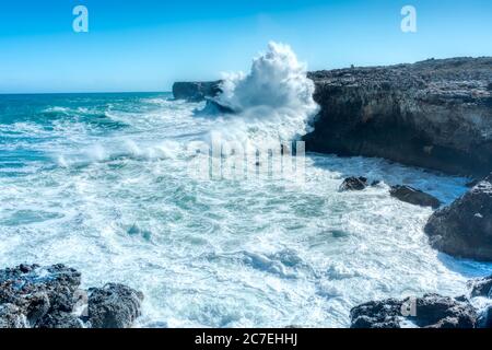 Horizontale Aufnahme von schönen Meereswellen und felsigen Hügeln unter Der klare blaue Himmel Stockfoto