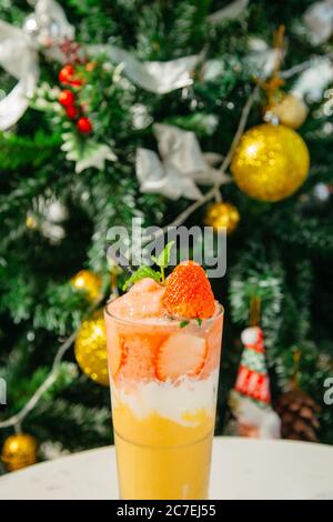 Vertikale Nahaufnahme eines Glases Cocktail und der Schöner Weihnachtsbaum im Hintergrund Stockfoto