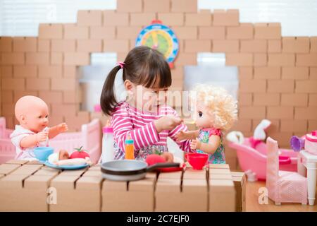 Kleinkind Mädchen vorgeben spielen Babysitting mit Baby-Puppe zu Hause Stockfoto