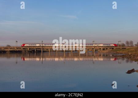 Eine Virgin Züge der Baureihe 221 Bombardier voyager Dieselzug in Mossband (nördlich von Carlisle) über den Fluss Esk Viadukt., im Fluss reflektiert. Stockfoto