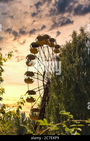 Ikonisches pripyat-Riesenrad in der Ausschlusszone bei einem goldroten Sonnenuntergang im Sommer. Roter, fast brennender Himmel, der auf die jüngsten Waldbrände und Waldbrände hinweist Stockfoto
