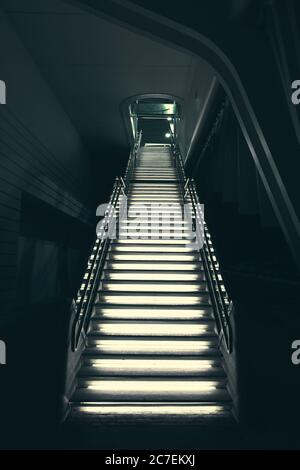 Vertikale Aufnahme von industriellen modernen grauen Steintreppen beleuchtet mit Leuchtet nach oben Stockfoto