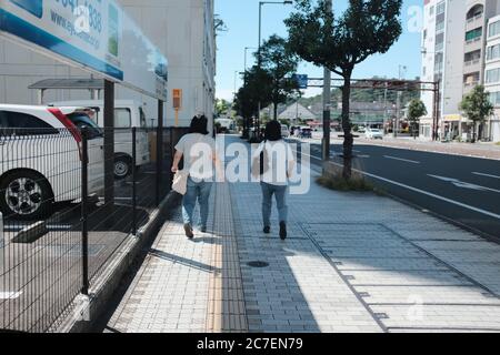 MATSUYAMA, JAPAN - 23. Sep 2019: Eine horizontale Aufnahme von zwei Freunden, die passende Outfits tragen und auf dem Bürgersteig spazieren gehen Stockfoto