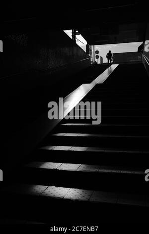 MATSUYAMA, JAPAN - 24. Sep 2019: Eine vertikale Graustufenaufnahme von Treppen in einem Tunnel und einer Person, die aus dem Tunnel geht Stockfoto