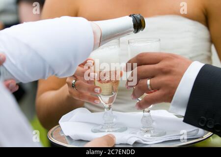 Flasche Champagner, die in Gläser pooring und toasten Stockfoto