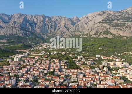 Luftaufnahme von Gebäuden in der Nähe der Berge unter einem klaren blauen Himmel bei Tag in Makarska, Kroatien Stockfoto