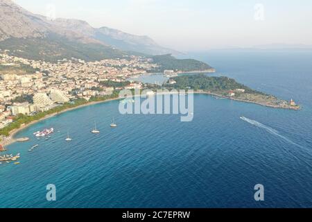 Hochwinkelaufnahme von Booten auf dem Wasser in der Nähe von Gebäuden unter einem bewölkten Himmel in Makarska, Kroatien Stockfoto