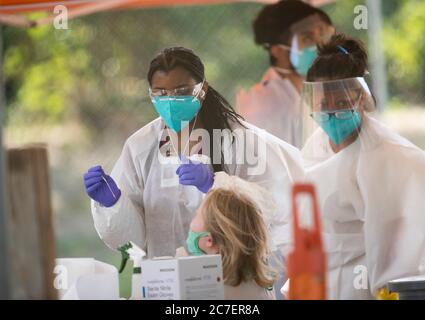 Austin, TX USA 15. Juli 2020:Medizinische Techniker, die für Austin Public Health arbeiten, ziehen Schutzkleidung (PSA) an und führen kostenlose COVID-19-Vorführungen in einem öffentlichen Park im Osten durch. Texas hat einen enormen Anstieg bei Coronavirus-Fällen mit fast 300,000 Fällen gesehen, die zu mindestens 3,432 Todesfällen geführt haben. Stockfoto