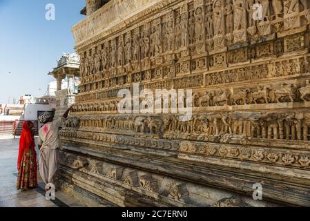 Ein Paar beobachten ein Kunstwerk an den Wänden des Jagdish Temple in Udaipur, Rajasthan geschnitzt Stockfoto