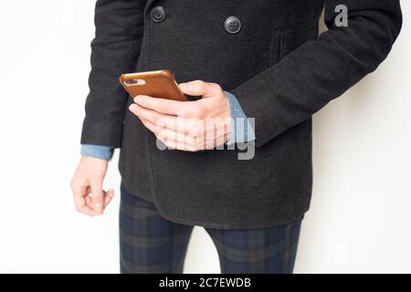Junger Mann in trendigen Business Casual Outfit hält Smartphone Stockfoto