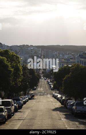 Vertikale Aufnahme einer bergab Straße mit Autos auf geparkt Die Seiten unter einem bewölkten Himmel Stockfoto