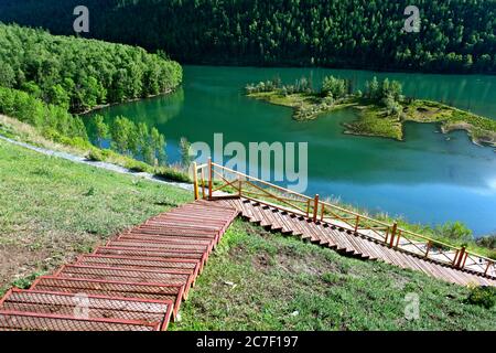 Horizontale Aufnahme des schönen Kanas See umgeben von Grün Bäume und rote Treppen in China Stockfoto