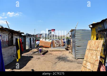 Kleidung und Bettwäsche trocknen auf der Wäscheleine in einem Slum in Soweto, Johannesburg, Südafrika. Die Orland Cooling Towers sind in der Ferne zu sehen Stockfoto