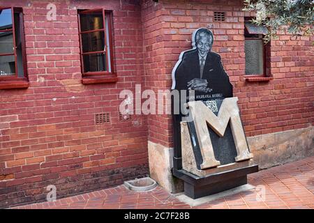 Das Mandela House in der Vilakazi Street in Orlando West, Soweto, Johannesburg. Ein Bild von Nelson Mandela mit einem großen M vor dem roten Backsteinhaus. Stockfoto