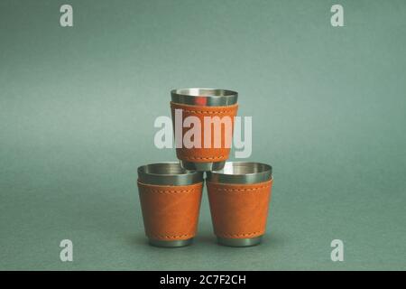 Metallic-Schnapsgläser. Ein Glas auf andere. Reise-Schnapsglas für Alkohol mit Lederhülle über dem Edelstahl. Persönliches Accessoire-Set Stockfoto