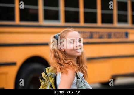 Glückliches Mädchen auf Schulbus aufgeregt für den ersten Tag der Schule. Fröhliche Schule Teenager. Bildung. Stockfoto
