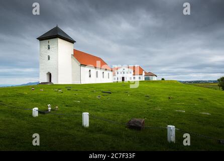 Einfache weiße Kirche und Turm sitzen in der Ebene Gelände vor Eine große Residenz in Island Stockfoto