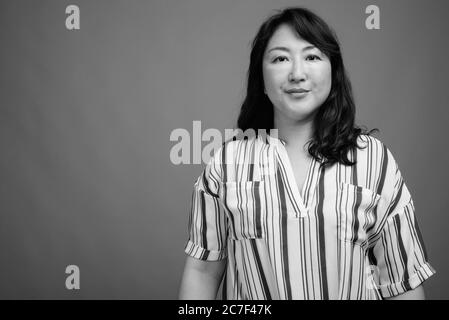 Reifen schöne asiatische Geschäftsfrau gegen grauer Hintergrund Stockfoto