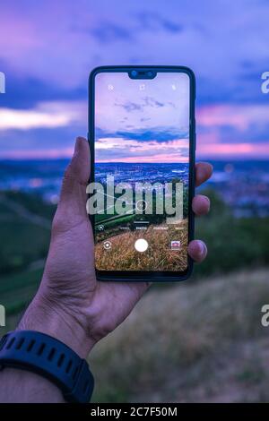 Vertikale Aufnahme einer Person, die ein Smartphone hält und nimmt Ein Bild einer urbanen Landschaft Stockfoto