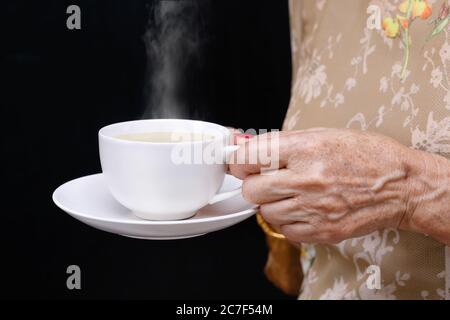 Ältere Frau hält eine Kaffeetasse. Stockfoto