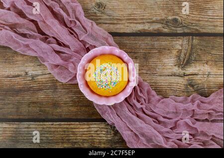 Cupcake mit Streuseln in rosa Schale auf Holzhintergrund. Draufsicht. Stockfoto