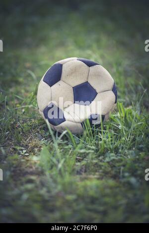 Vertikale Nahaufnahme eines abgenutzten Fußballs in einem Grasfeld Stockfoto