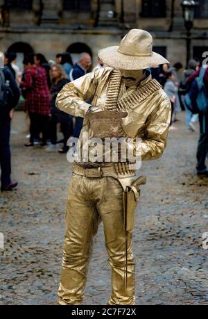 Straßenkünstler in goldenen Kleidern gibt vor, eine Statue zu sein Stockfoto