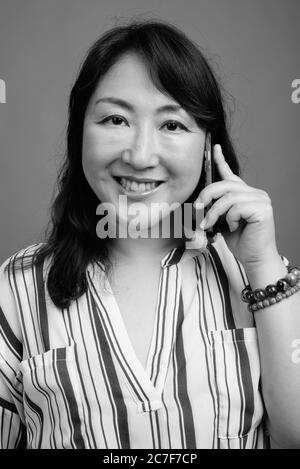 Porträt von reifen schönen asiatischen Geschäftsfrau mit Telefon Stockfoto