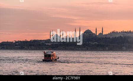 Boot auf dem Bosporus, Silhouette der Blauen Moschee und Hagia Sophia, bei Sonnenuntergang, Istanbul, Türkei Stockfoto