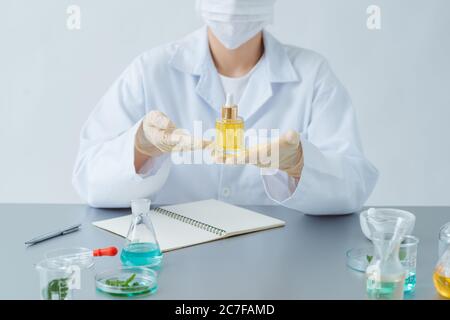 Weibliche Dermatologin hält Flasche Hautpflegeprodukt am Tisch, Nahaufnahme Stockfoto