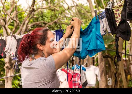 Eine junge Erwachsene Frau aus einem weniger entwickelten Land hängt die Wäsche auf der Linie im Hof. Stockfoto