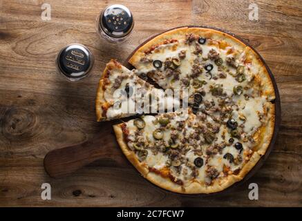 Pepperoni Pizza auf Holzbrett, Draufsicht auf leckere und knusprige vegetarische Pizza Margherita auf hellbraunem Tischhintergrund Stockfoto