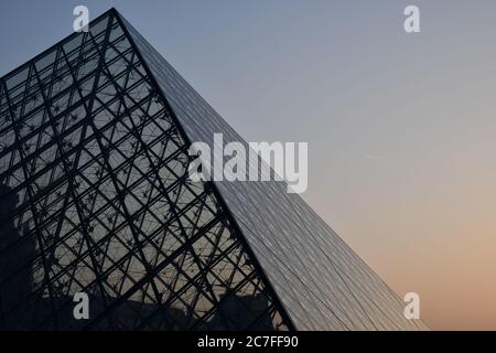 Pyramidenförmige Glaskuppel vor klarem Himmel bei Sonnenuntergang. Futuristische transparente Glas Dachkonstruktion von Dreieck geometrische Form Stockfoto