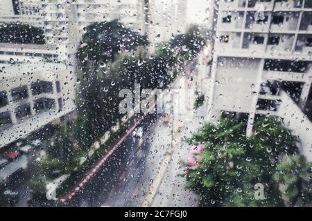 Regen auf der Straße, Luftbild. Wassertropfen auf Glas Wohnung Fenster gefangen. Blick auf die Straße während Sturm. Nasse Straße und vorsichtiges Fahren Co Stockfoto