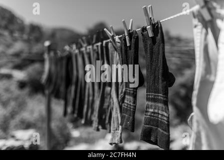 Die Graustufen der gewaschenen Socken auf der Linie im Feld Umgeben von Hügeln unter der Sonne Stockfoto