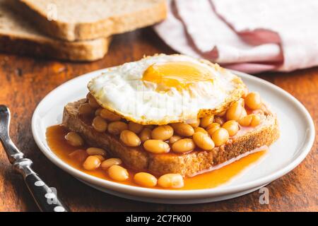 Toast mit Spiegelei und gebackenen Bohnen auf dem Teller. Stockfoto