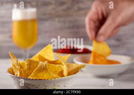 Eine Person taucht Tortilla Chips in Nacho-Sauce. Stockfoto