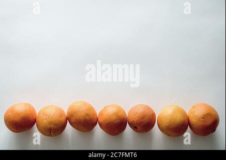 Neben jedem reiht sich eine Landschaft mit frischen, köstlichen Mandarinen an Andere auf einer weißen Oberfläche Stockfoto