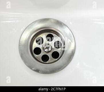 Ablassen von Wasser mit einem Edelstahlgitter in einem alten, lang genutzten Waschbecken im Badezimmer Stockfoto