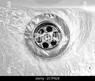 Ablassen von Wasser mit einem Edelstahlgitter in einem alten, lang genutzten Waschbecken im Badezimmer Stockfoto