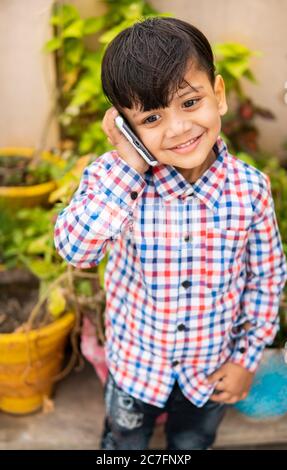 Outdoor-High-Winkel-Bild von niedlichen kleinen Jungen im Gespräch auf dem Smartphone. Stockfoto