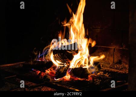 Ein Kamin mit einer schönen Flamme, Holz und brennende Glut beleuchtet. Perfekt für Restaurants, Pizzerien und Gaststätten. Stockfoto