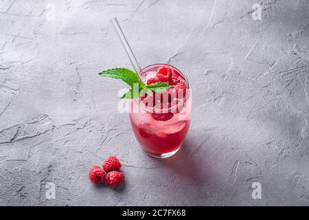 Frisches, eiskalter Beerensaft-Getränk mit Minze, Sommerlimonade aus Himbeer im Glas mit Strohhalmen auf steinbetontem Hintergrund, Winkelansicht Stockfoto