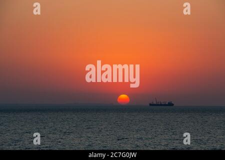 Silhouette eines Fischerschiffes auf einem Hintergrund von Sonnenaufgang. Sonnenaufgang am Morgen am Meer. Stockfoto