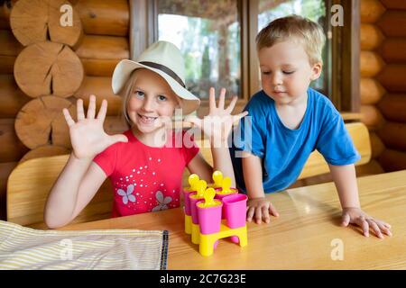 Zwei niedliche liebenswert kaukasischen blonde kleine Geschwister sitzen am Tisch Haushof und haben Spaß machen mit Mama hausgemachte Obst Eis. Junge glückliche Kinder Stockfoto