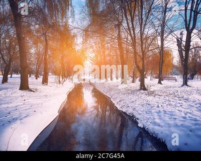 Landschaftlich schöner Blick auf den Fluss und die Bäume mit dem ersten Schnee. Gefallene Blätter auf dem Schnee Stockfoto