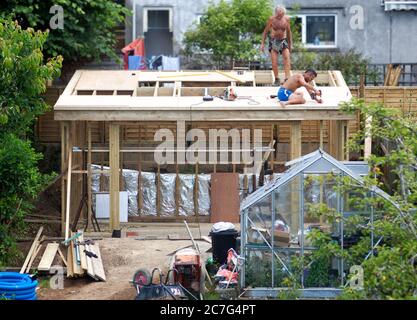 Zwei Bauherren, die das Dach eines Gartenstudios bauten Stockfoto