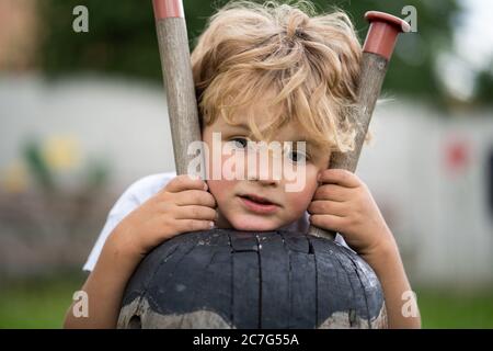 Unglücklicher kleiner Junge, der auf Schaukel sitzt Stockfoto